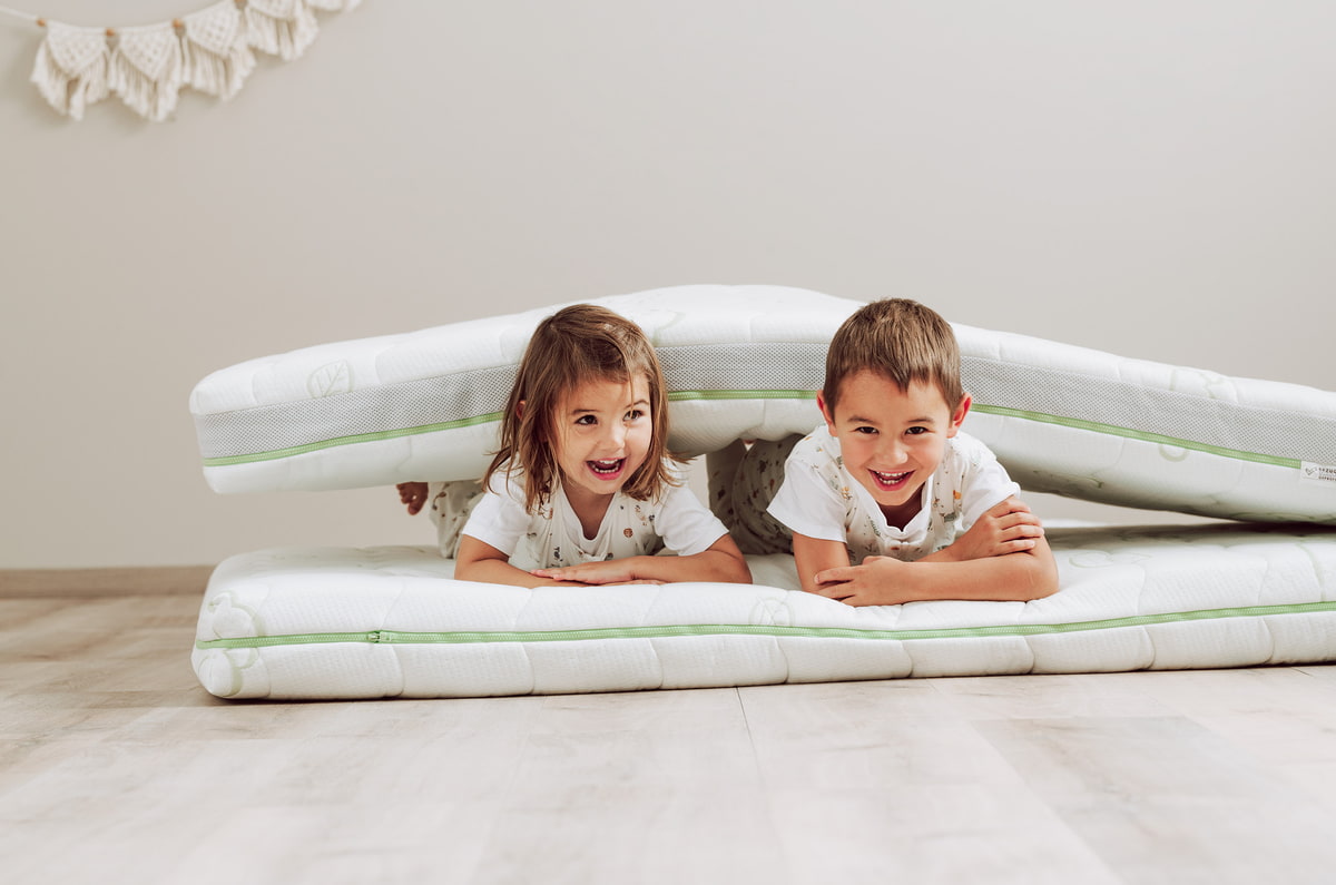 Kinder liegen am Boden auf Kindermatratze
