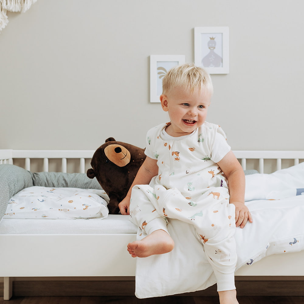 Kind in Schlafsack mit Füßen mit Dinosauriern Kind mit Schlafsack mit Füßen in Bett