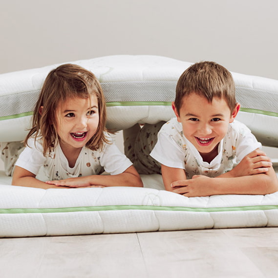 Kinder mit Schlafsack auf Matratze kinder-schlafsack-mit-fuessen-spielen-boden