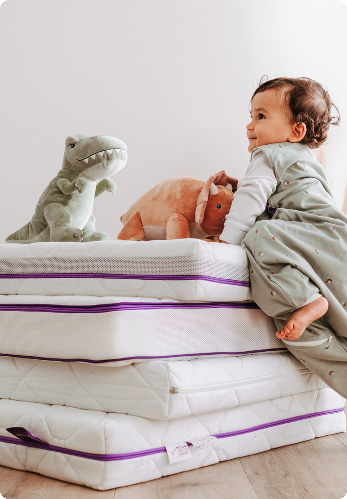 Baby klettert auf Matratzenstapel