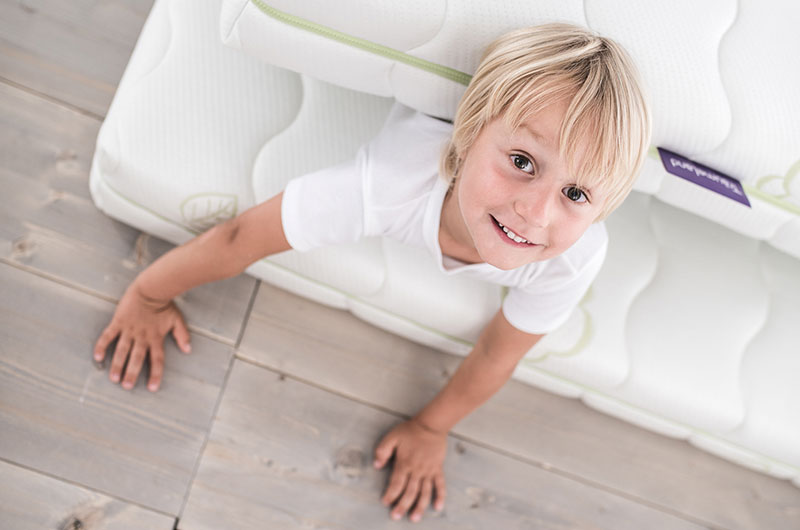 Kleiner Junge auf Kindermatratze Kleiner Junge auf einer Träumeland Kinder- und Jugendmatratze