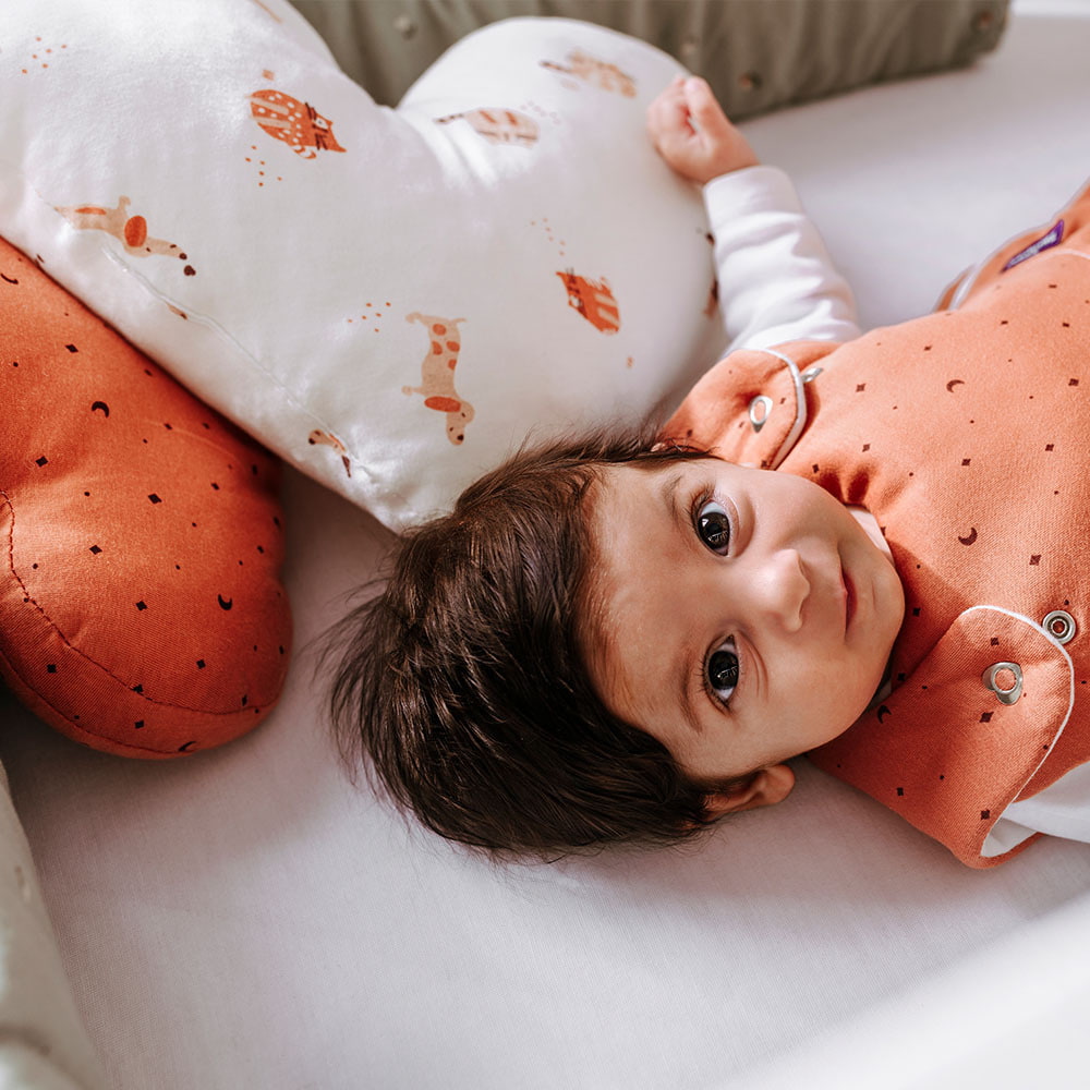 Baby im Gitterbett mit Kuschelkissen Herz
