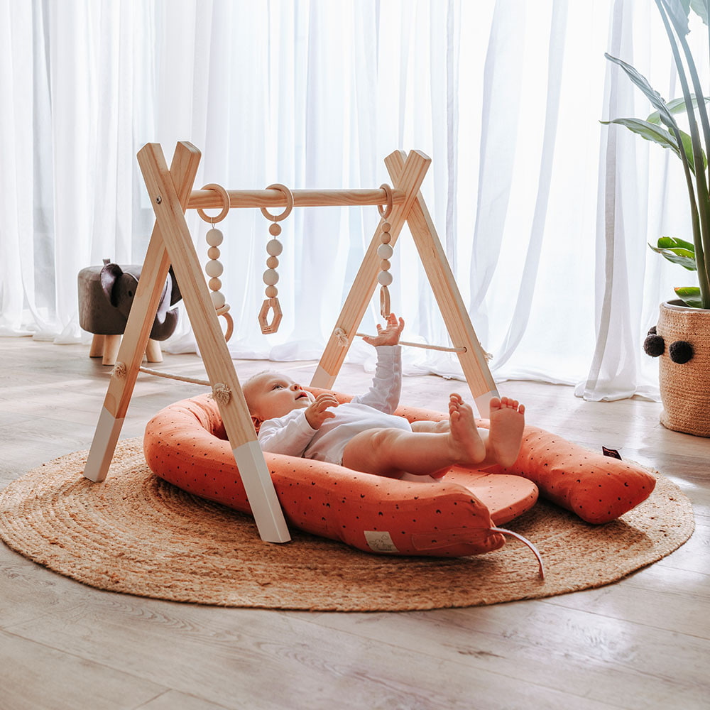 Baby spielt mit Spielebogen im Home Nest