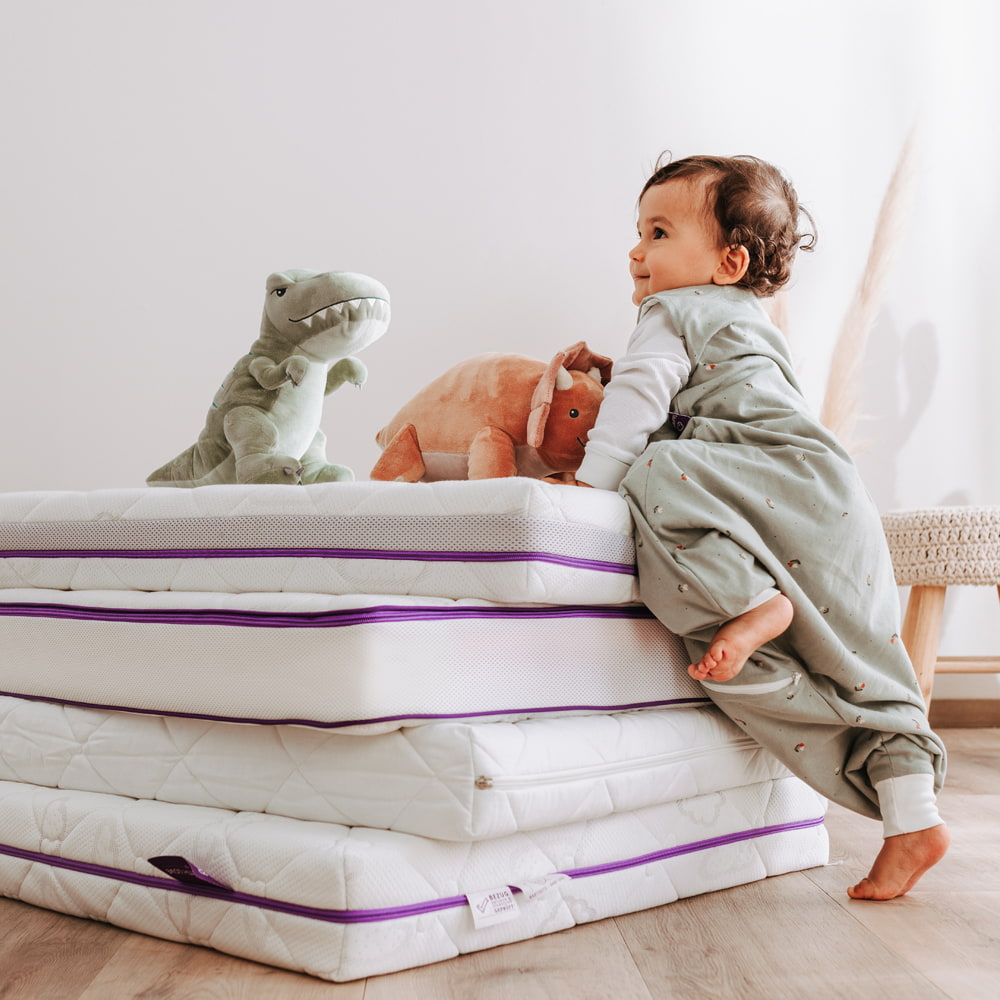 Baby klettert auf Matratzenstapel
