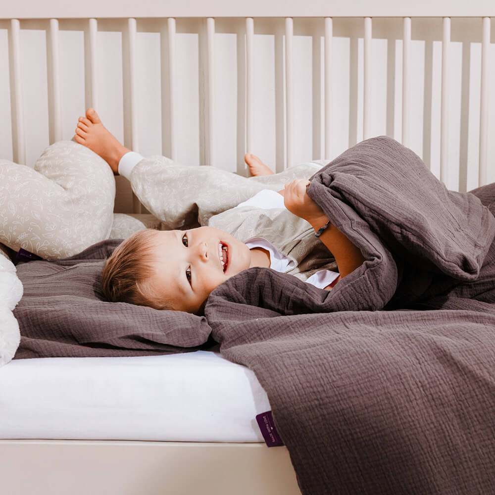 Kind kuschelt im Bett mit kuscheliger Bettwäsche Kind kuschelt im Bett mit kuscheliger Bettwäsche