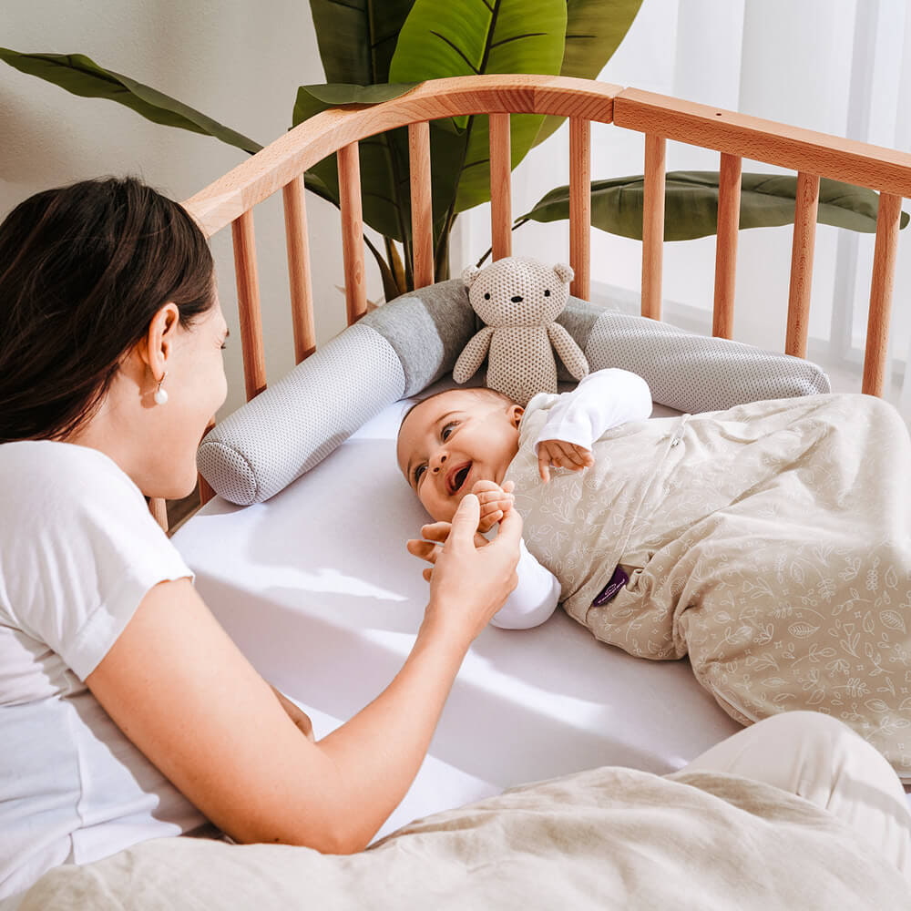 Baby im Beistellbett mit Nestverkleinerung und Schlafsack